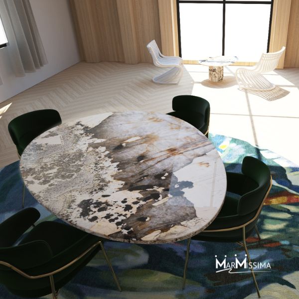 Vista dall’alto di un tavolo ovale in marmo con venature artistiche, circondato da sedie scure e posizionato su un tappeto colorato con motivi floreali in un ambiente moderno.